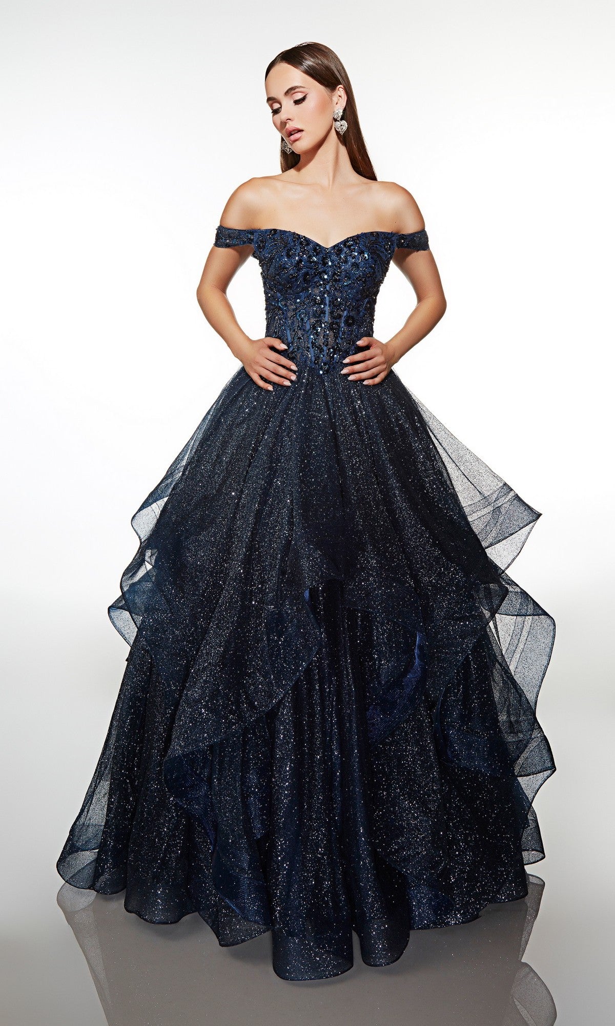 A woman poses against a white background in the Alyce 62173 long formal dress—a midnight, off-the-shoulder prom gown with sparkling details and a layered glitter tulle skirt.